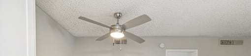 an empty living room with a ceiling fan and a kitchen